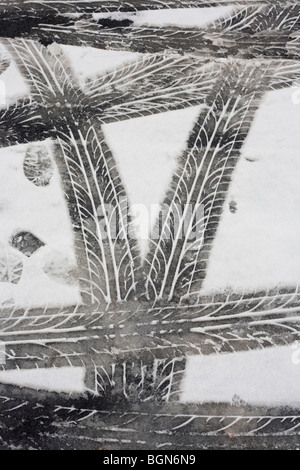 Lauffläche Reifenspuren (Reifen) sind als abstrakte Muster auf Schneeschmelze nach schlechtem Wetter auf den Londoner Straßen links. Stockfoto