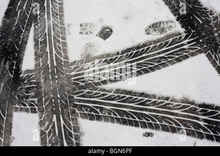 Lauffläche Reifenspuren (Reifen) sind als abstrakte Muster auf Schneeschmelze nach schlechtem Wetter auf den Londoner Straßen links. Stockfoto