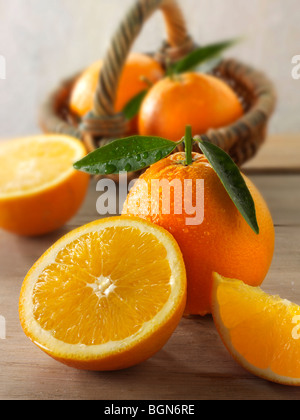 Frische Orangen ganze und geschnittene Hälften mit Blättern in einer Küche-Einstellung Stockfoto