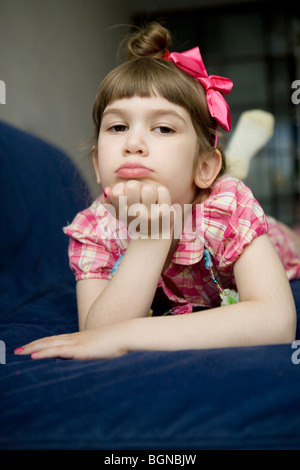 schwere Mädchen auf einem Sofa auf dem Bauch liegend mit seine Hände ruhen auf seinem Kinn Stockfoto