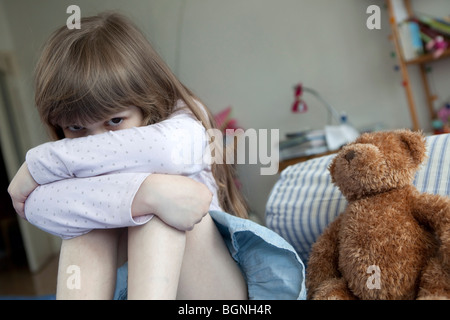 kleine süße Mädchen sieben Jahre alt am Bett sitzen und Weinen Stockfoto