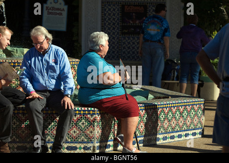 Senioren ruhen durch das sitzen auf einem Brunnen Rand. Stockfoto