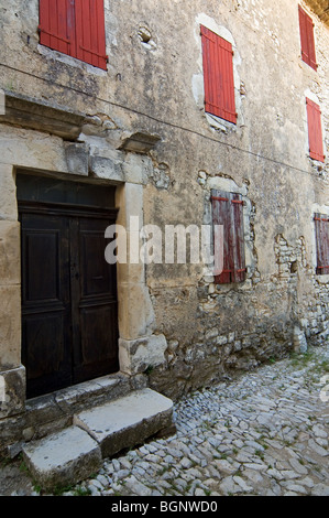 Alte traditionelle Häuser mit roten Holz Markisen / Fenster Rollläden in Gasse am Banon, Alpes-de-Haute-Provence, Provence, Frankreich Stockfoto