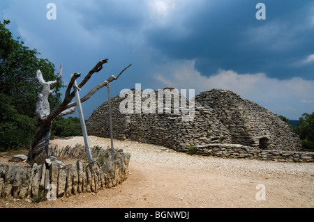 Verdreht Mandelbaum im restaurierten Dorf Les Bories mit seinen traditionellen Stein gallischen Hütten, Gordes, Provence, Frankreich Stockfoto