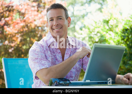 Porträt eines reifen Mannes vor einem Laptop sitzen und Lächeln Stockfoto