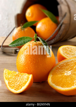 Ganze und geschnittene frische Orangen inmitten der Küche Stockfoto