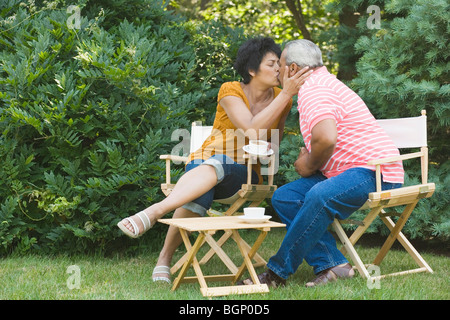 Reife Frau küssen einen älteren Mann in einem Garten Stockfoto