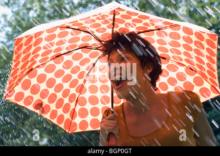 Reife Frau, die unter einem Dach bei Regen und schreien Stockfoto