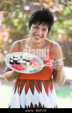 Porträt einer reifen Frau Sushi mit Stäbchen zu essen Stockfoto