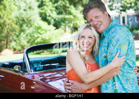 Porträt von ein älteres Paar umarmen einander und lächelnd vor Cabrio Stockfoto
