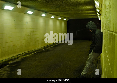 Teenager gegen U-Bahn in der Nacht an der Wand lehnend, London UK Stockfoto