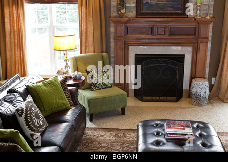 Wohnzimmer mit Leder-Sofa und Couchtisch, gepolsterten Stoff Sessel, Kamin und Teppichboden Stockfoto