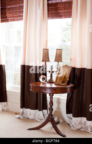 Freistehender Tisch mit Schublade durch die Fenster mit passenden Vorhänge im Schlafzimmer eingerichtet. Details Stockfoto