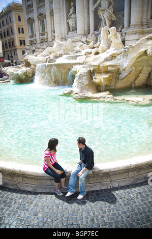 Junges Paar sitzt am Trevi-Brunnen Stockfoto