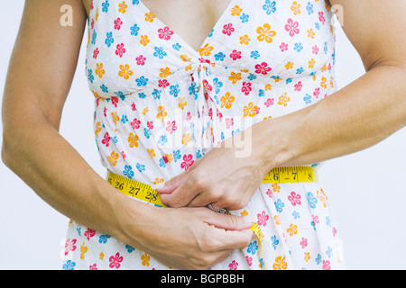 Mitte Schnittansicht einer Frau messen Sie ihre Taille mit einem Maßband Stockfoto