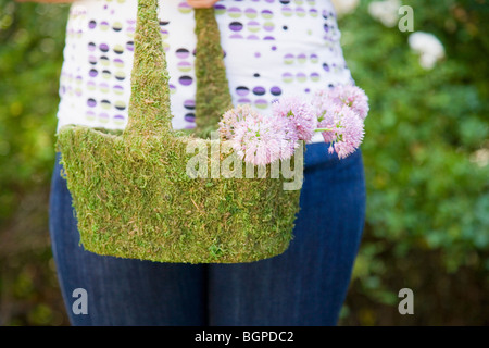 Mitte Schnittansicht einer jungen Frau hält einen Korb mit Blumen Stockfoto