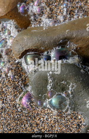 Felsen sitzen in den Sand bedeckt mit bunten Bubbles auf eine Cornwall Nordstrand Stockfoto