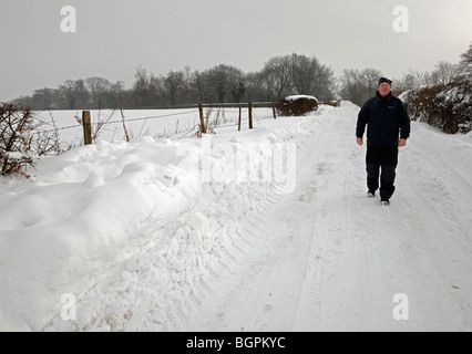 Mann, in einer verschneiten Straße entlanggeht. Stockfoto