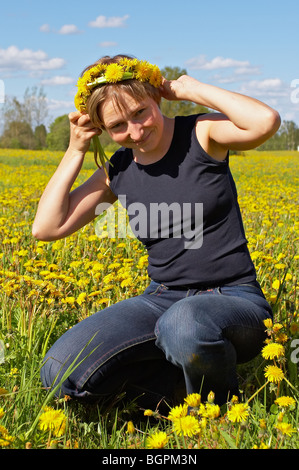 junge Frau mit Löwenzahn Kranz auf schöne Wiese Stockfoto
