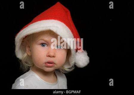 blonde Mädchen in großen Weihnachten Weihnachtsmütze, isoliert auf schwarz Stockfoto