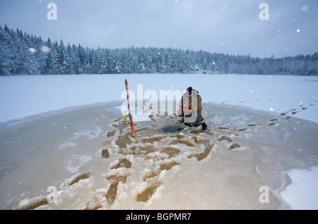 Älterer Mann Check-Fischernetze im Winter, Finnland Stockfoto