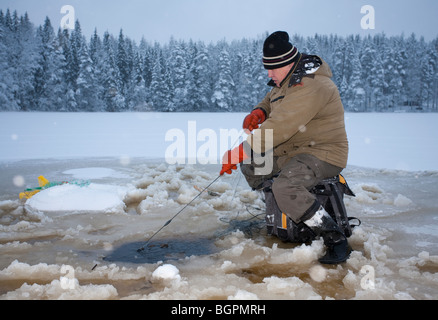 Älterer Mann Check-Fischernetze im Winter, Finnland Stockfoto