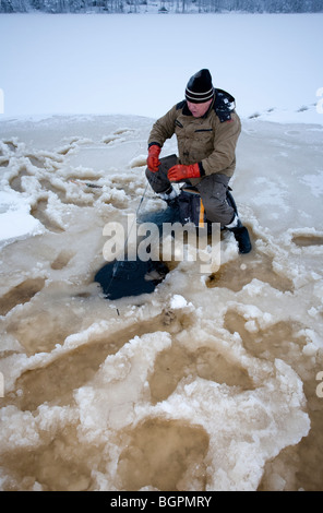 Älterer Mann Check-Fischernetze im Winter, Finnland Stockfoto