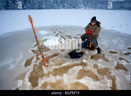 Älterer Mann Check-Fischernetze im Winter, Finnland Stockfoto