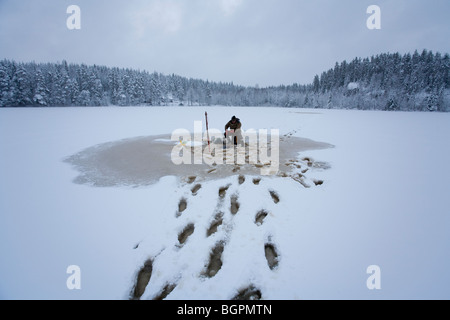 Älterer Mann Check-Fischernetze im Winter, Finnland Stockfoto