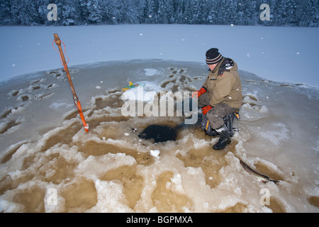 Älterer Mann Check-Fischernetze im Winter, Finnland Stockfoto