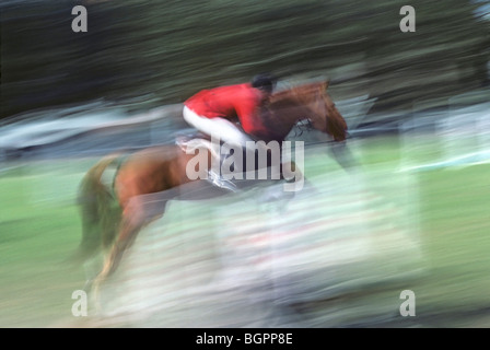 Ein Fahrer über einen Zaun in ein Pferd springen Meisterschaft vorbei. Bewegungsunschärfe betonen den Sprung. Stockfoto