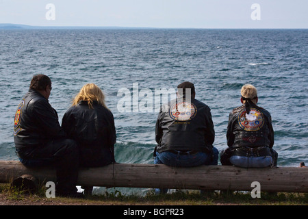 Amerikanische Biker zwei Paare, die auf einem Ufer sitzen Harley Davidson Kleidung Lifestyle von hinten aussichtsreiche Menschen in den USA Hi-res Stockfoto