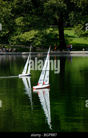 Zwei Modell-Segelboote gleiten parallel über das Modell Boat Basin im Central Park in New York City. Stockfoto