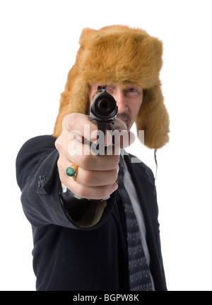 Ein Mann im schwarzen Anzug und Pelzmütze hält eine Pistole und richtete sie auf Kamera. Isoliert auf weiss Stockfoto