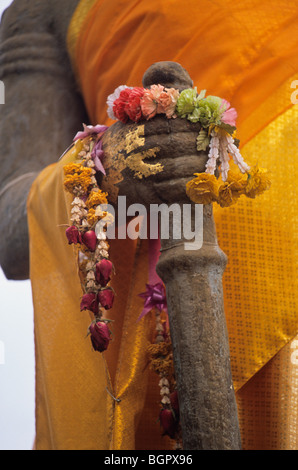 Am Wat Phu Champasak in der Nähe von Pakse, Laos, Detail der drapierten Buddha-Statue mit Blume Angebot und Spazierstock. Stockfoto