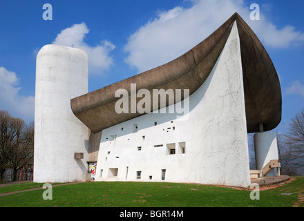 Bescheidene Kirche von Le Corbusier ist kongruent zur Landschaft. Betonbau mit geschwungenen Dach ist von unten fotografiert. Stockfoto