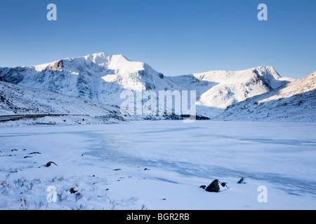 Ogwen Valley, North Wales, UK. Blick über den zugefrorenen Llyn Ogwen See, Y Garn mit Schnee bedeckten Bergen im winter Stockfoto