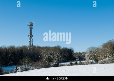 Handy-Mast mit Schnee vor blauem Himmel. Gelegen in der Nähe von Stroud in Cotswolds. Stockfoto