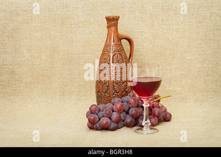 Stillleben aus einem Ton-Flasche, Trauben und Wein gegen eine Leinwand Stockfoto