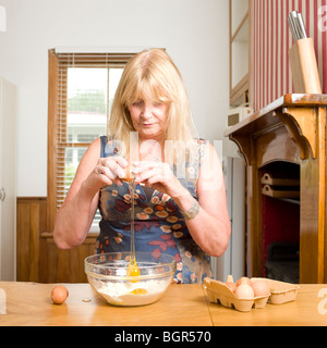 Frauen cracking Eiern in mischen Schüssel Mehl mit Eiern Shell als nächstes Bowl Stockfoto