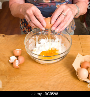 Frauen cracking Eiern in mischen Schüssel Mehl mit Eiern Shell als nächstes Bowl Stockfoto