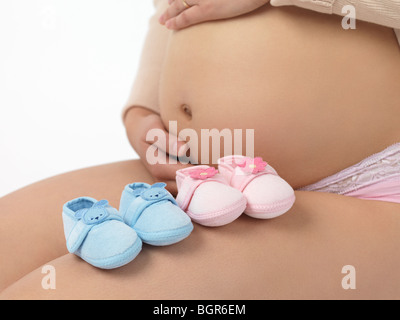 Schwangere Frau mit blauen und rosa Baby-Schuhe Stockfoto