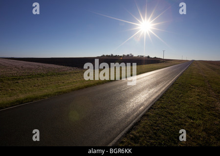 Sonne über lange leere Landstraße Stockfoto