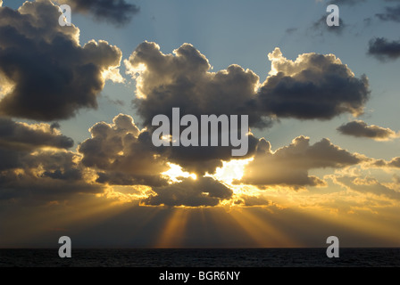 Dramatischer Sonnenaufgang (oder Sonnenuntergang, falls erforderlich) Mit Sonnenstrahlen oder Sonnenstrahl des Sonnenlichts, der durch die Dunkelheit platzt Wolken und klarer blauer Himmel über und darüber hinaus Stockfoto