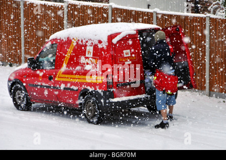 Kalte Winterwetterszene schneit auf Royal Mail Delivery Postbote Arbeiten von Postauto in Wohnstraße im Schneesturm Brentwood Essex England Großbritannien Stockfoto