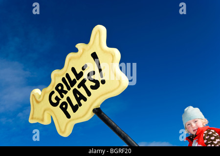 Ein Mädchen von einem gelben Schild unter dem blauen Himmel, Schweden. Stockfoto