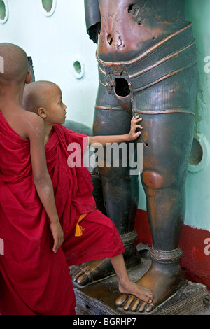 Junge buddhistische Mönche die Khmer Bronze Skulptur berühren. Mahamuni Paya. Mandalay. Myanmar Stockfoto