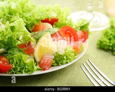 Frischer Salat mit Tomaten und Lachs in eine weiße Schale auf einer grünen Tischdecke Stockfoto