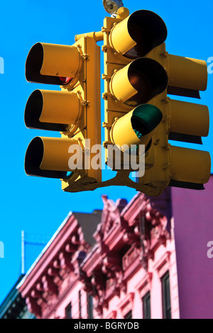 New York-Ampeln vor blauem Himmel mit rosa Gebäude im Hintergrund Stockfoto