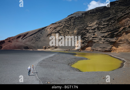 Touristen auf der Suche bei El Charco de Los Clicos oder The Emerald Lake in der Nähe von El Golfo auf Lanzarote auf den Kanarischen Inseln an einem Sommertag Stockfoto